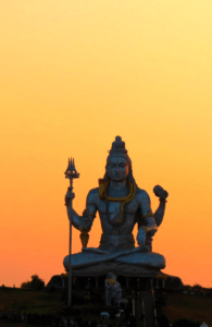 Statue of the Hindu Lord Shiva with sunset in the background